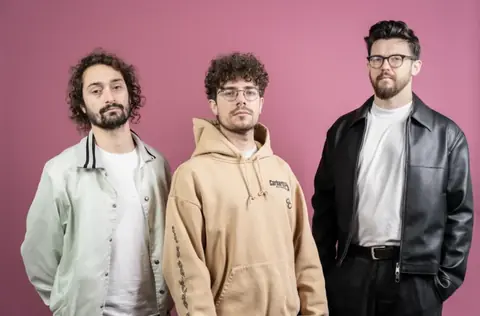 Les trois musiciens de Jean-Paul Groove, trio électro bruxellois, posent devant un fond rose